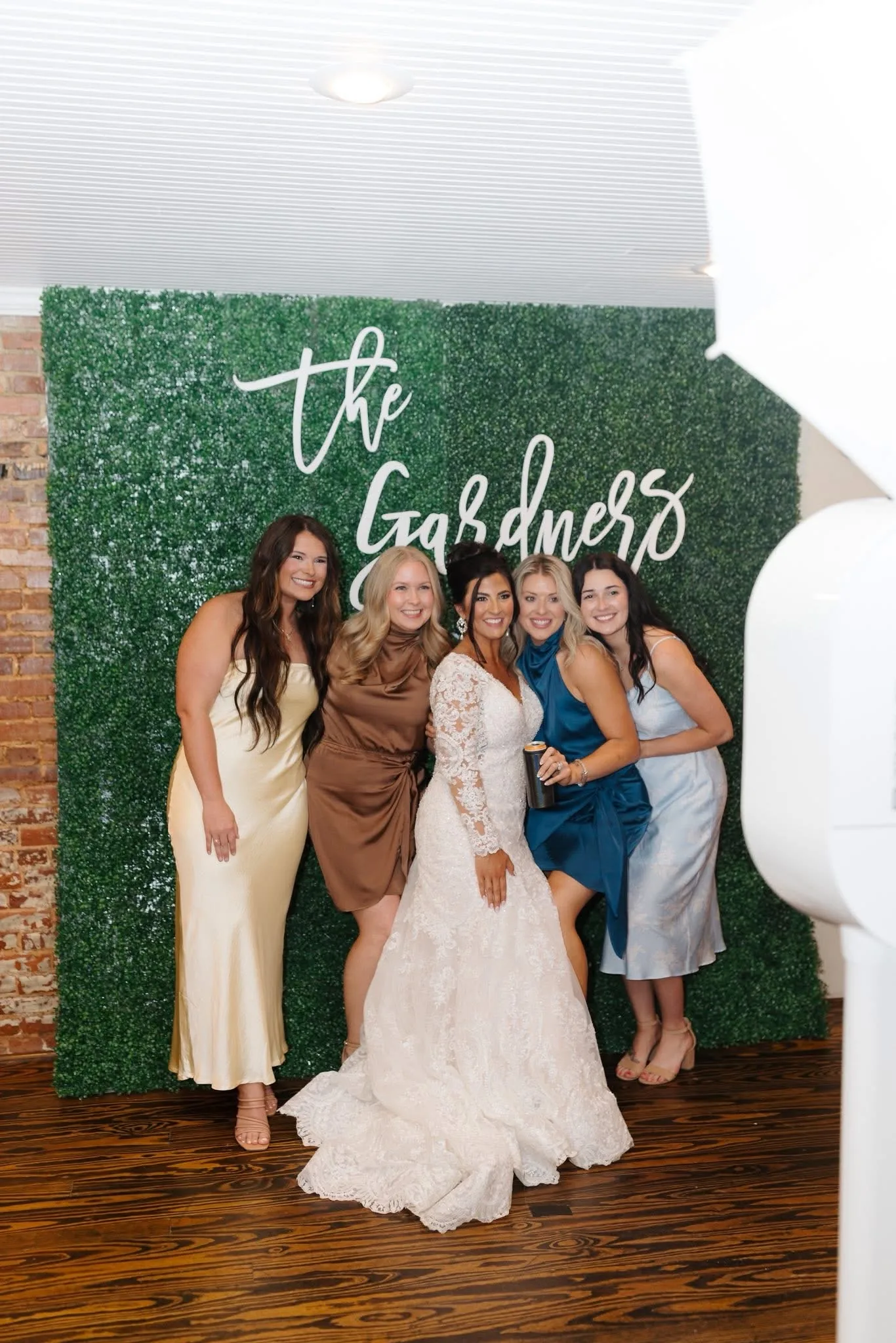Bride and guests in the booth, with the venue's exposed brick wall at the edge of the frame.