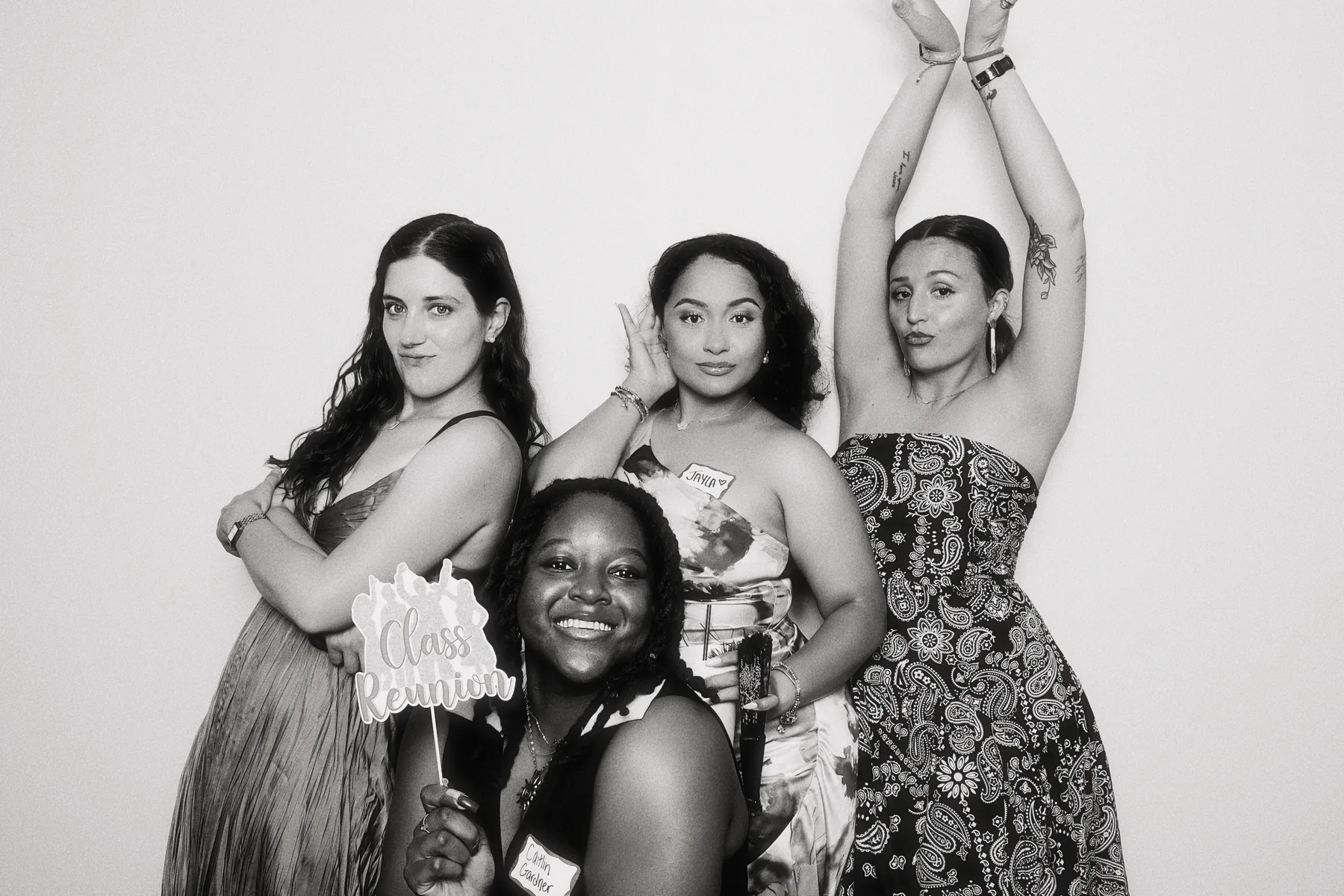 Guests at a class reunion holding a prop sign in the booth.