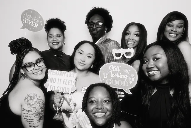 Group of friends holding photo booth prop signs.