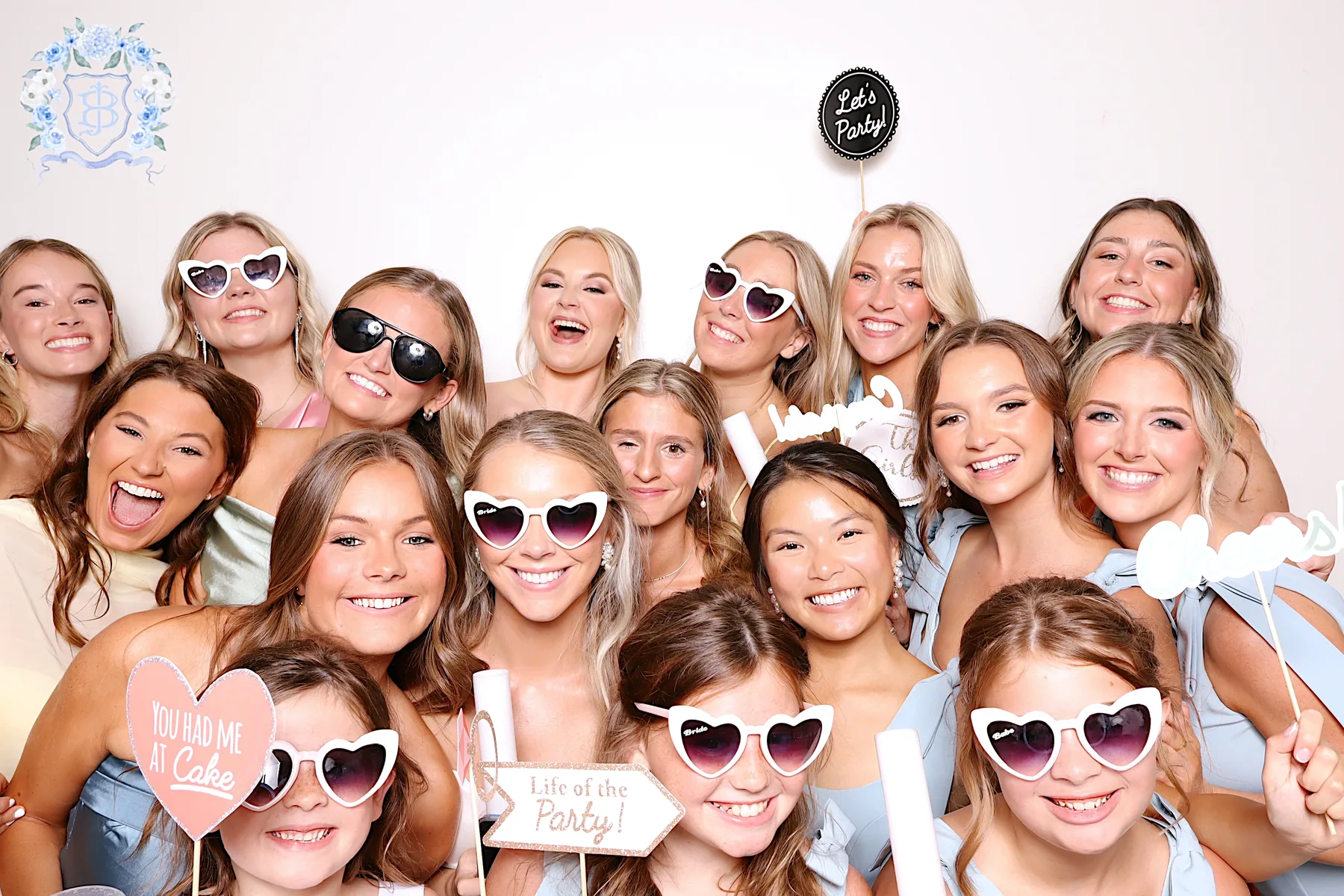 A crowd of guests packed into the booth against a plain cream backdrop.